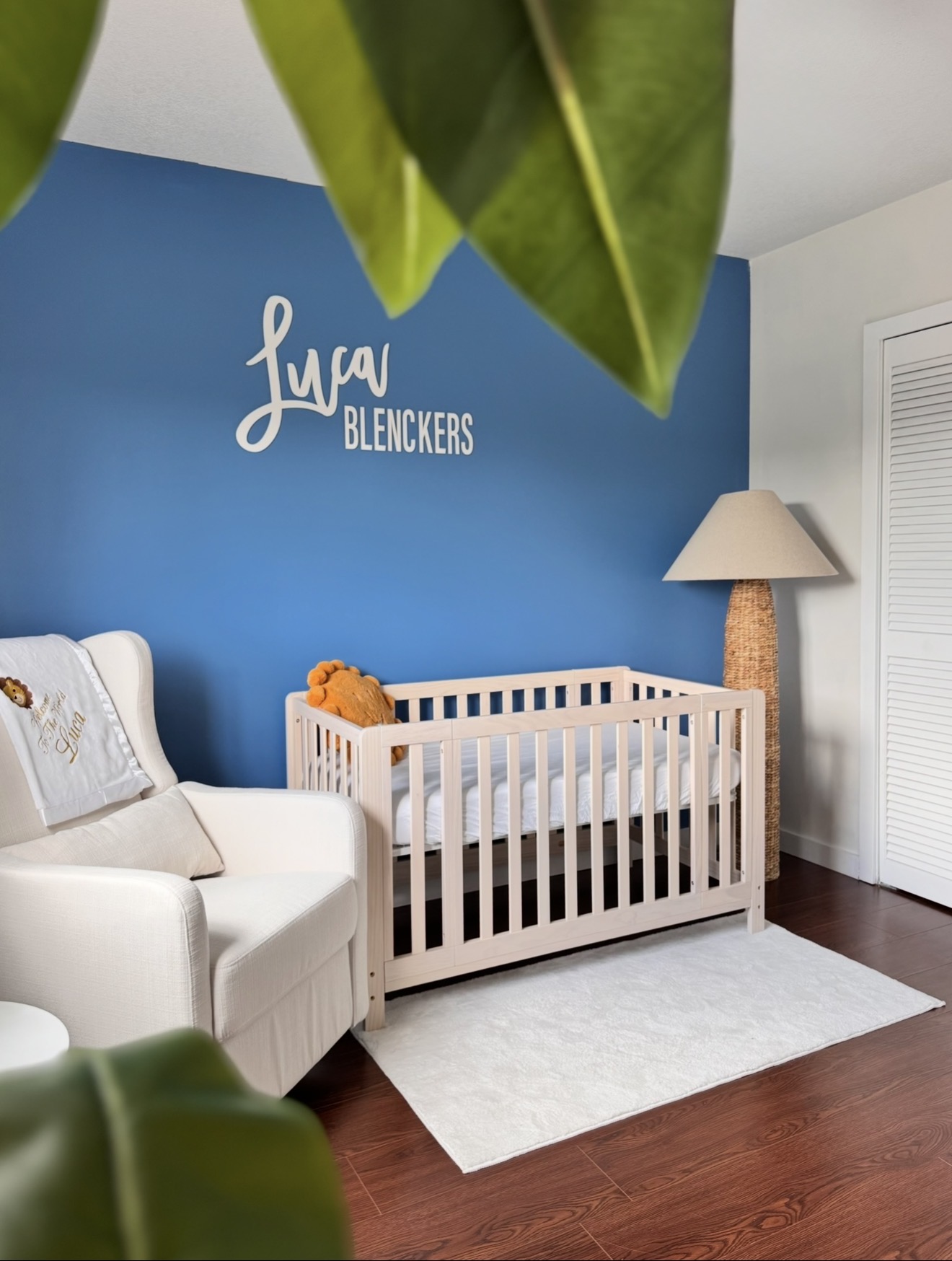 Blue nursery with a white crib and reading chair